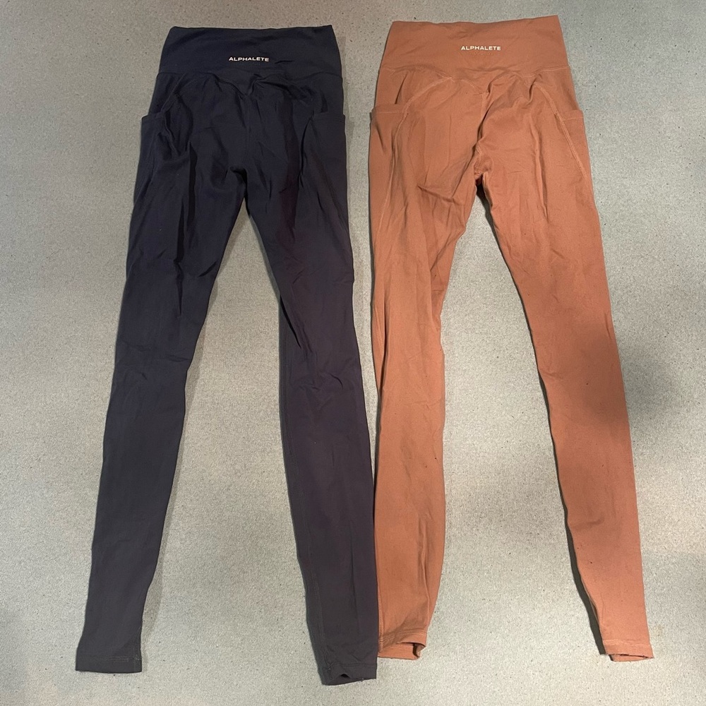 Two pairs of Alphalete alphalux leggings, both in size XS, greenish blue & cream